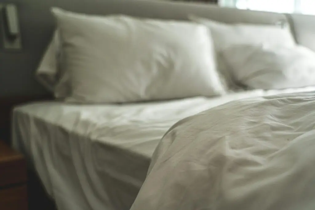 Elegant white bed linen with soft pillows creating a warm and inviting atmosphere.